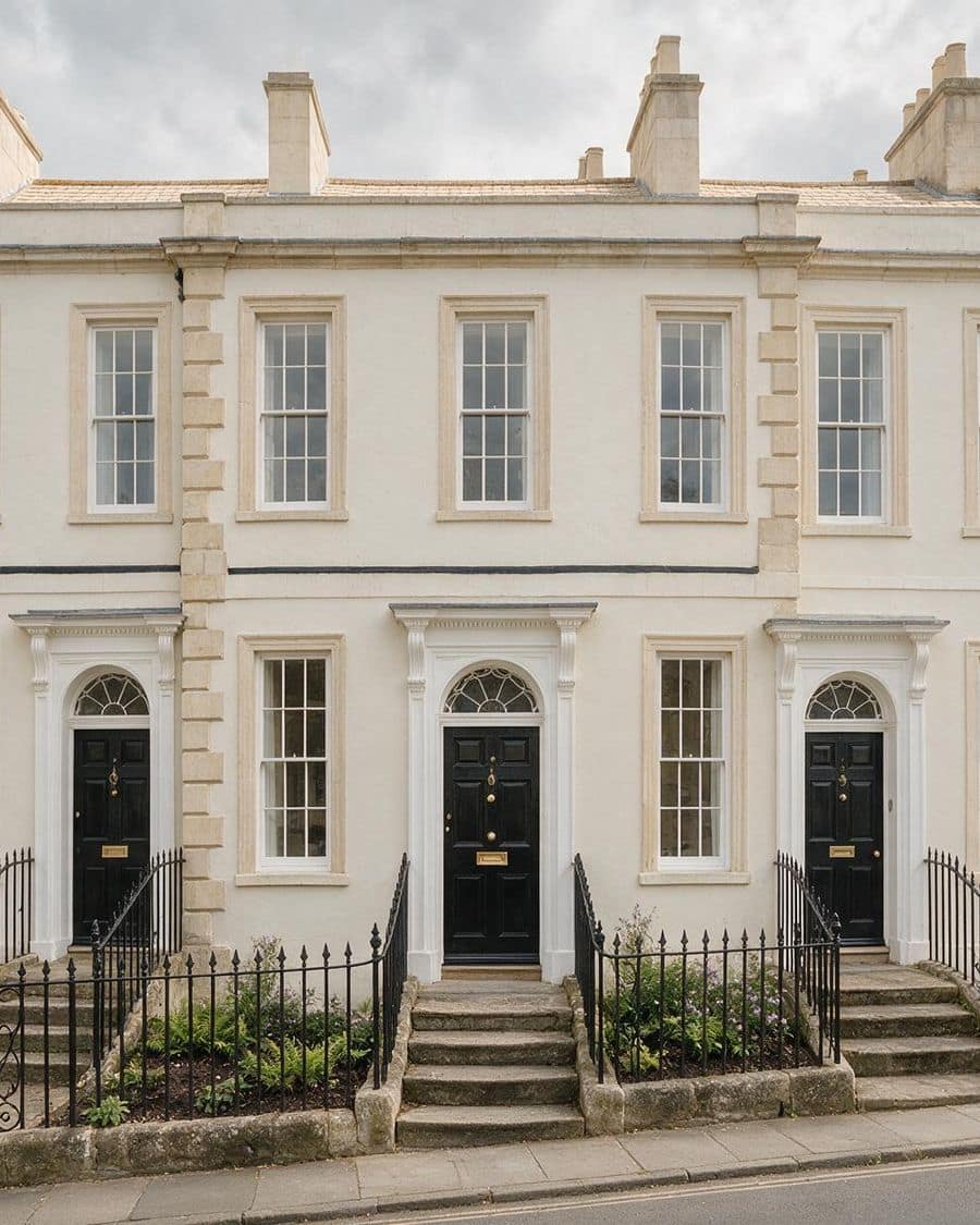 A pair of period townhouses with pillared doorways, railings and steps.